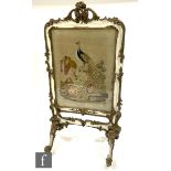 A Victorian white painted and gilt embroidered firescreen decorated with a peacock perched on a