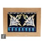 A Moorcroft Pottery framed rectangular panel decorated with two tubelined stylised leaves within