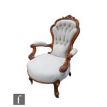 A Victorian carved walnut framed easy elbow chair, shaped back over scroll arms, upholstered in pale
