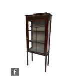 A small Edwardian line inlaid mahogany display cabinet enclosed by a bar glazed door, on square