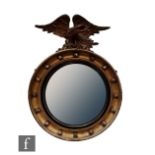 A small Regency gilt circular wall mirror, ebonised line and ball interior surmounted with a