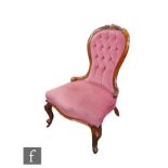 A Victorian carved walnut balloon back easy chair on cabriole legs, upholstered in pink buttoned