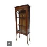 An Edwardian line inlaid mahogany display cabinet enclosed by a swept bar glazed door, glazed sides,
