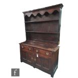 A George III oak dresser fitted with two drawers over a paneled cupboard base below a two tier