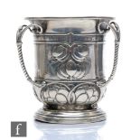 An Arts and Crafts hallmarked silver tyg part decorated with berries and terminating in three ribbed