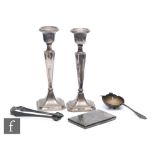 Five items of hallmarked silver to include a pair of candlesticks, a card case, a tea strainer and a