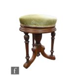 A late 19th Century circular walnut revolving piano stool, on urn pedestal and fluted triple base,