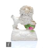 A small 19th Century Staffordshire model of a dog stood upon a floral basket with encrusted hair,