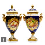A matched pair of Coalport pedestal vases each decorated with hand painted cartouche panels of fruit