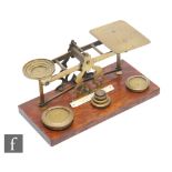 An Edwardian set of brass postal scales and weights, on oak base, width 27cm.