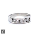 A platinum hallmarked diamond five stone ring, channel set brilliant cut stones to a plain shank,