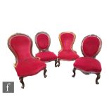 A harlequin group of four Victorian carved walnut easy chairs, each upholstered in crimson
