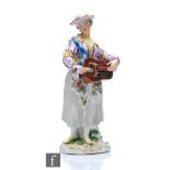 A 19th Century Meissen figure of a lady stood playing a Hurdy Gurdy, dressed in a striped bodice