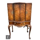 A 1930s Queen Anne style figured walnut cocktail cabinet by Maple & Co London, the revolving door