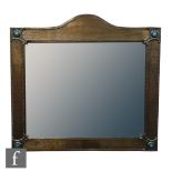 An Arts and Crafts pewter framed bevelled wall mirror, with arch top to the frame and beaded