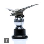 A Desmo chrome car mascot in the form of a winged eagle with outstretched wings perched on a ball,