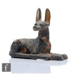 An Egyptian Anubis guardian seated with head turned to the right, painted black, cloth interior with