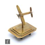 A brass trench art model of an aeroplane, mounted to a stepped rectangular base with canted corners,