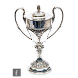 An Arts & Crafts hallmarked silver twin handled trophy cup and cover, part decorated with floral