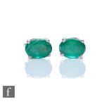 A pair of silver set single stone emerald stud earrings, oval claw set stones, length 8mm, total