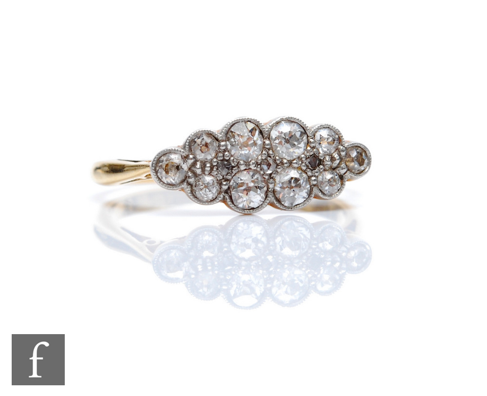 An early 20th Century 18ct diamond elongated oval cluster ring, ten millgrain set old cut stones