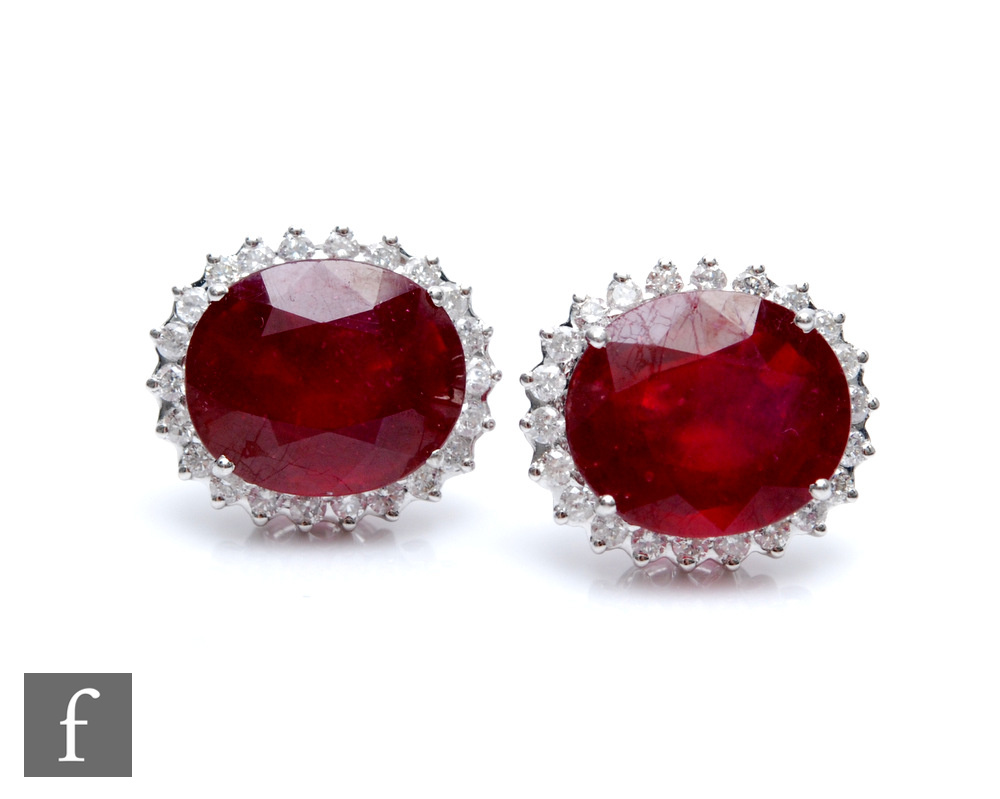 A pair of 18ct white gold ruby and diamond cluster stud earrings, central facet cut, claw set oval