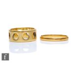 An 18ct hallmarked wedding ring with pierced circular disc decoration, weight 6.5g, ring size M,