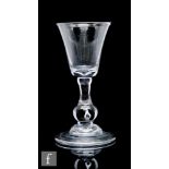 An 18th Century balustroid drinking glass circa 1740, with high round funnel bowl above an