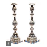 A pair of hallmarked silver candlesticks each with plain shaped square base below foliate