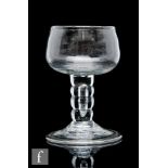 An 18th Century drinking glass circa 1740, the ovoid bowl raised to a four section bobbin stem