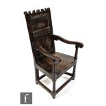 An oak wainscot chair in the 17th Century style, the fielded panel back above a solid seat and