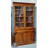 A late Victorian walnut cabinet bookcase, with cornice pediment, the glazed double doors above a