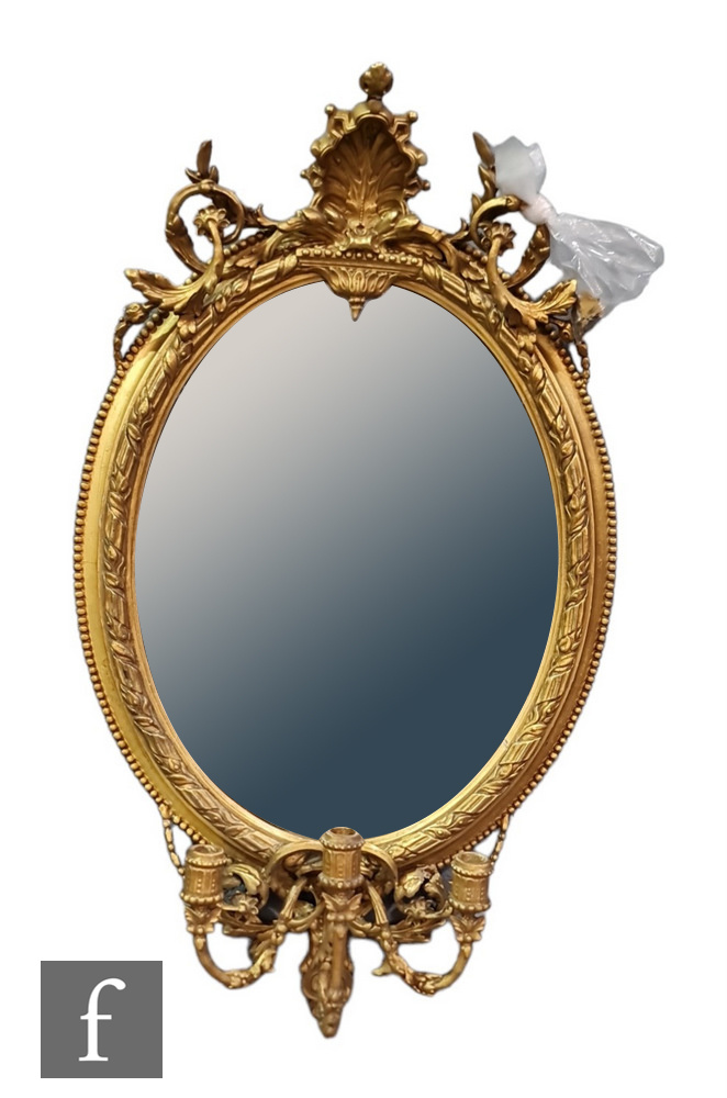A late 19th to early 20th Century girandole wall mirror of oval form within a moulded gilt and gesso