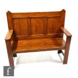 An early 20th Century oak two seat settle, with triple fielded panel back over the solid seat,
