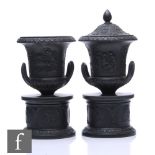 A pair of late 19th to early 20th Century Wedgwood black basalt campana urns and covers affixed to a