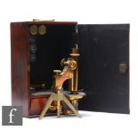 An early 20th Century brass microscope in wooden case, unnamed, on tripod stand, with spare lenses