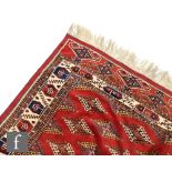 A 20th Century Kazak rug of red ground colour, with hooked diamond shaped repeat pattern guls to the