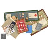 A collection of Red Cross memorabilia to include a framed group of badges awarded to Miss E M