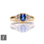 An 18ct hallmarked sapphire and diamond ring, central oval collar set sapphire flanked by three