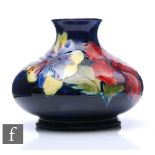 A Moorcroft Hibiscus vase of squat form, the blue ground tubeline decorated with pink, purple and