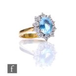An 18ct hallmarked aquamarine and diamond cluster ring, central oval aquamarine, length 9mm,