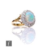 An 18ct hallmarked opal and diamond cluster ring, central oval opal, length 10mm, within a border of