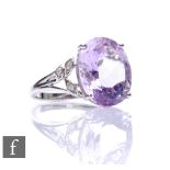 A 9ct white gold amethyst and diamond ring, central oval amethyst with three diamonds to scrolled