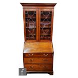 A George III mahogany bureau bookcase enclosed by a pair of astragal glazed doors below a fluted
