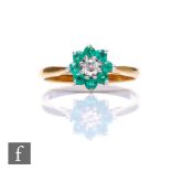 An 18ct emerald and diamond cluster ring, central brilliant cut diamond within a border of eight