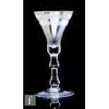 An 18th Century drinking glass circa 1750, the slender thistle bowl with upper engraved rim with