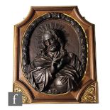 A late 19th century carved wall plaque of Christ with a halo, raised hand and holding a sphere,