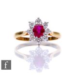 An 18ct hallmarked ruby and diamond cluster ring, central oval ruby, length 5mm, within a border