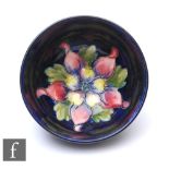 A small Walter Moorcroft bowl of footed circular form, decorated in the Columbine pattern on blue,