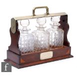 An Edwardian inlaid walnut three bottle tantalus with plated mounted handle on plinth base with key,